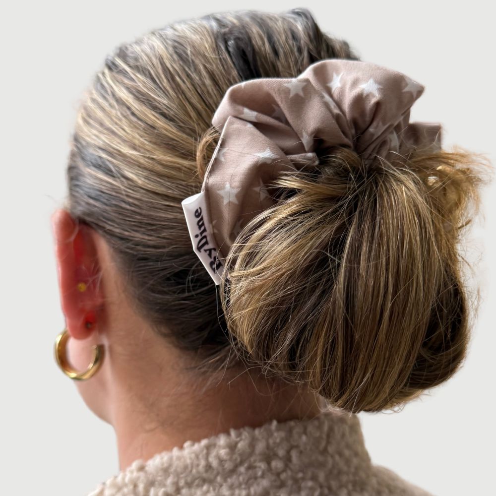 Scrunchie in taupe kleur met witte kleine sterren van katoen gedragen in haar BYDINE